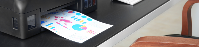 Kontorsskrivare som skriver ut färgglada diagram och rapporter på skrivbord.